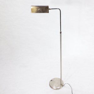 May include: A silver floor lamp with a rectangular shade and a long, adjustable arm. The lamp has a round base and a black cord.