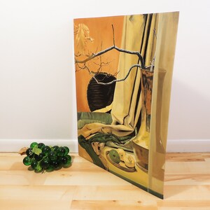 May include: A still life painting depicting a vase with a dried branch and leaves, a draped fabric, and fruit on a plate. The background is a warm orange colour with a dark circle.