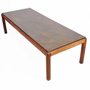 May include: A long, rectangular coffee table with a dark wood frame and a glass top. The glass top has a subtle pattern.
