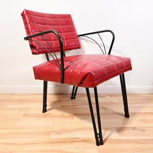 May include: A red upholstered chair with a black metal frame. The chair has a quilted seat and back.