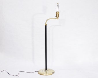 May include: A black and brass floor lamp with a curved arm and a round base. The lamp has a simple design and is in good condition.