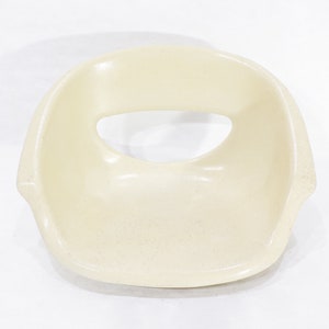 May include: A white plastic chair seat with a large oval opening in the centre.