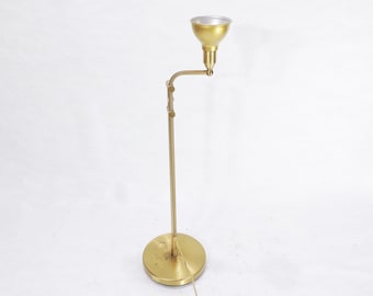 May include: A gold floor lamp with a single adjustable arm and a round shade. The lamp has a simple, modern design.