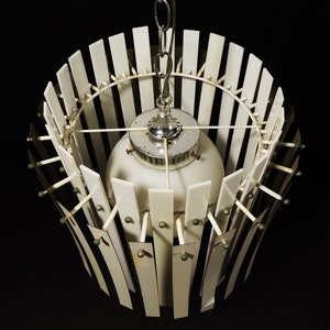 Może przedstawiać: Biało-srebrny żyrandol w stylu mid-century modern z białym kloszem szklanym i geometrycznym wzorem.