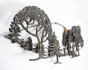 Pode incluir: Uma escultura de parede de metal que representa uma cena de floresta com árvores e uma cerca. A escultura é feita de metal escuro e tem um visual rústico e vintage.