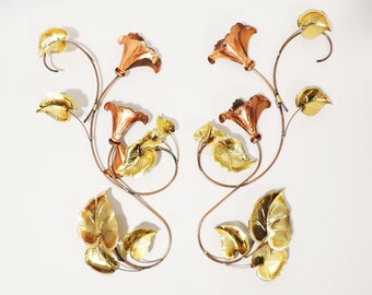 May include: A wall sculpture featuring stylised copper and gold flowers with leaves. The flowers are trumpet-shaped and the leaves are stylised and have a textured surface.
