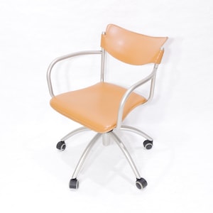 May include: A tan leather office chair with silver metal arms and base. The chair has five wheels.