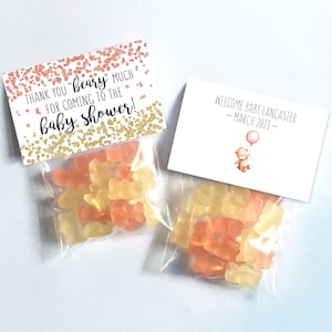 May include: Two small clear bags filled with gummy bears. One bag has a pink and gold thank you tag that reads "Thank you "Beary" much for coming to the baby shower!" The other bag has a white tag that reads "Welcome Baby Lancaster - March 2021 -" with a small illustration of a teddy bear holding a pink balloon.