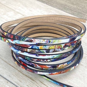 May include: A close-up of a stack of colourful leather cord with a black edge. The cord has a marbled pattern with shades of blue, red, yellow, and white.
