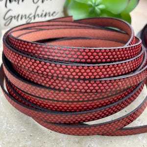 May include: Red leather cord with a polka dot pattern. The cord is rolled up and is approximately 1/2 inch wide.