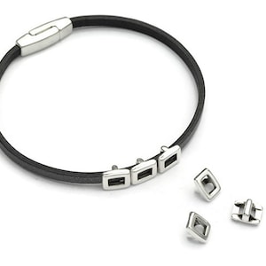 May include: A black leather bracelet with a silver clasp and four silver square-shaped charms.