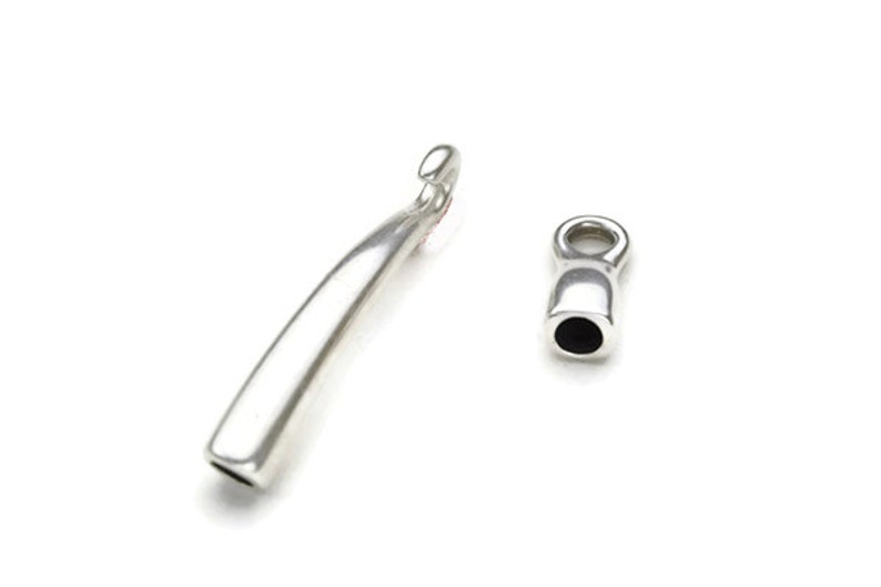 May include: Two silver metal jewelry end caps. One end cap is a long, curved, hook-shaped piece. The other end cap is a small, round, barrel-shaped piece with a small loop at the top.