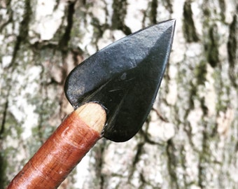 May include: A close-up of a black arrowhead attached to a wooden shaft wrapped in brown leather.