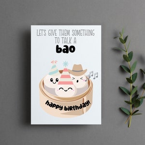 May include: A white card with a funny birthday greeting. The text reads "Let's give them something to talk a bao."  The card features a cartoon illustration of three bao buns with faces, wearing party hats and a cowboy hat. The text "happy birthday!" is written below the bao buns.