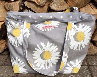 May include: A gray tote bag with white daisy print and white polka dots. The bag has a pink label with the text "Abbey's" on it.