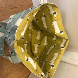 May include: A blue and white striped tote bag with a yellow lining featuring a repeating pattern of white dachshunds with black ears and noses.