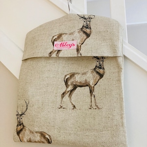 May include: A beige linen laundry bag with a brown deer print. The bag has a pink label that says "Abbeys Handmade with Love".
