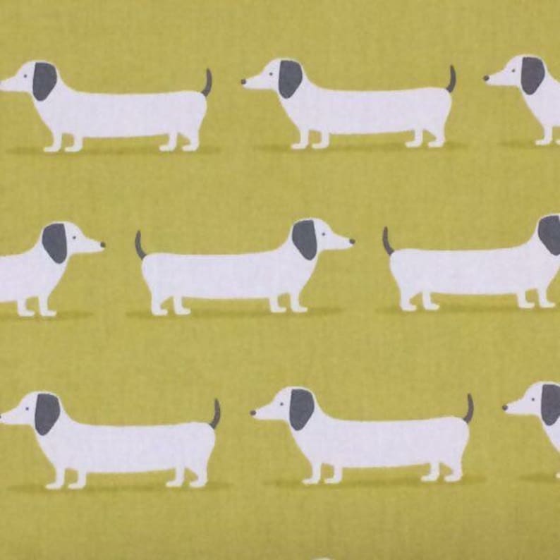 May include: A repeating pattern of white dachshunds with black ears and noses on a yellow background.