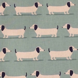 May include: A repeating pattern of white dachshunds with black ears and noses on a light blue background.