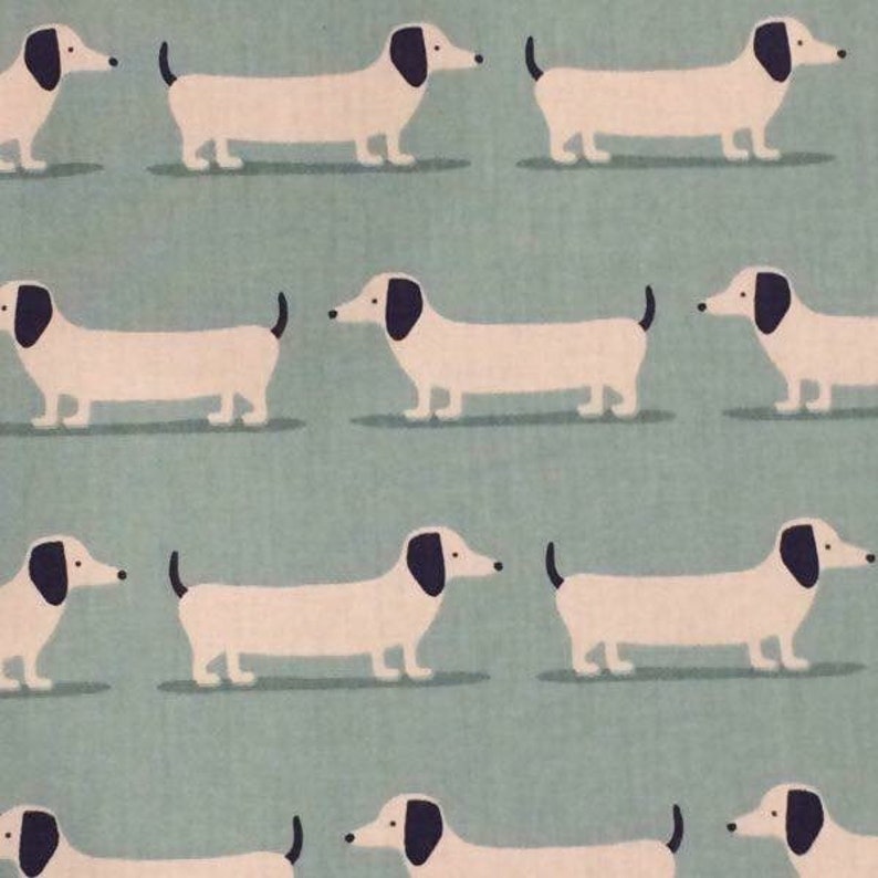 May include: A repeating pattern of white dachshunds with black ears and noses on a light blue background.