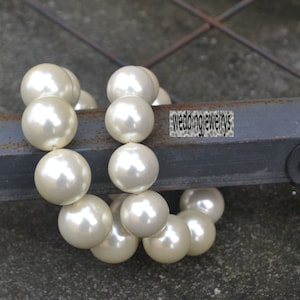 May include: A strand of white pearl beads, strung together to form a necklace or bracelet. The pearls are round and smooth, and they are arranged in a simple, elegant design.