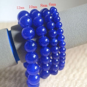 May include: Four strands of blue gemstone beads, each strand with a different size bead: 12mm, 10mm, 8mm, and 6mm. The beads are round and smooth, with a glossy finish.
