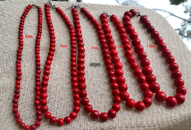 K&ouml;nnte beinhalten: F&uuml;nf Str&auml;nge roter Edelsteinperlen, jede mit einer anderen Gr&ouml;&szlig;e: 6 mm, 8 mm, 10 mm, 12 mm und 14 mm. Die Perlen sind rund und haben eine glatte, polierte Oberfl&auml;che.