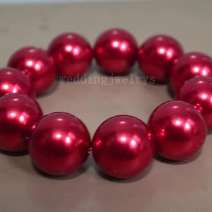 May include: A bracelet composed of large, round, glossy red beads. The beads are evenly spaced and strung together to form a circular shape. The text "weddingjewelrys" is visible.