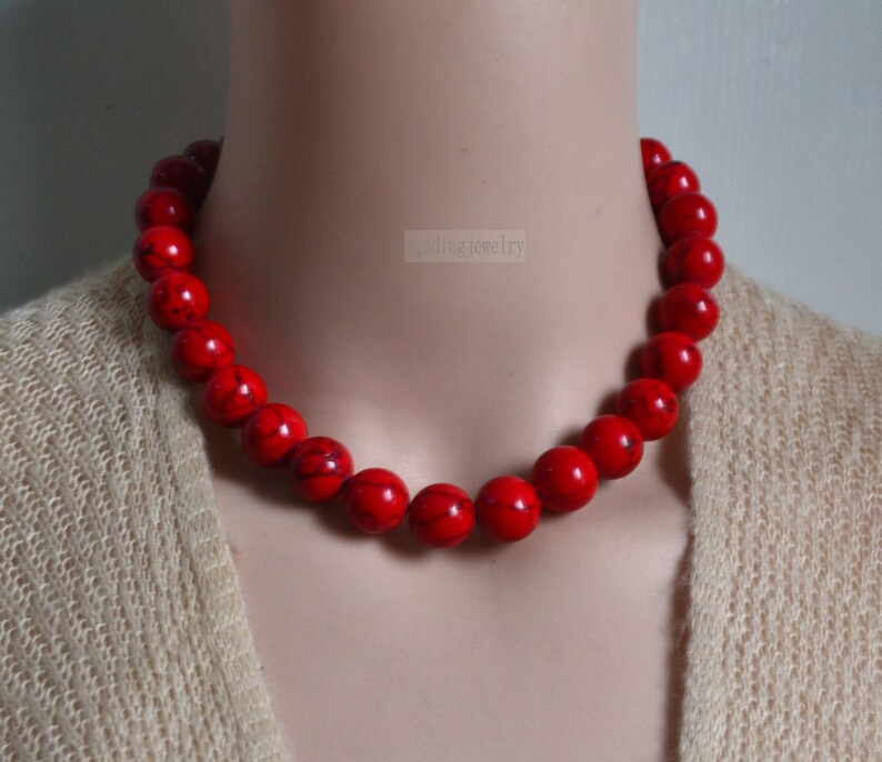 K&ouml;nnte beinhalten: Eine rote Perlenkette aus runden, glatten Steinen. Die Kette befindet sich an einem Mannequin-Hals und ist etwa 46 cm lang.