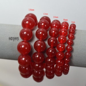 May include: Six red gemstone bracelets with different sized beads. The bracelets are labeled with their bead size in millimeters: 14mm, 12mm, 10mm, 8mm, and 6mm.