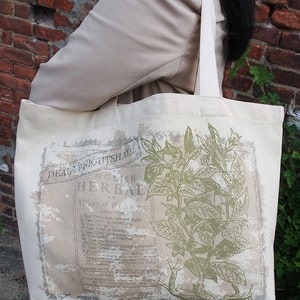 Op de afbeelding: Een witte canvas tote bag met een groene botanische illustratie en de tekst "English Herbal" en "Deadly Nightshade".
