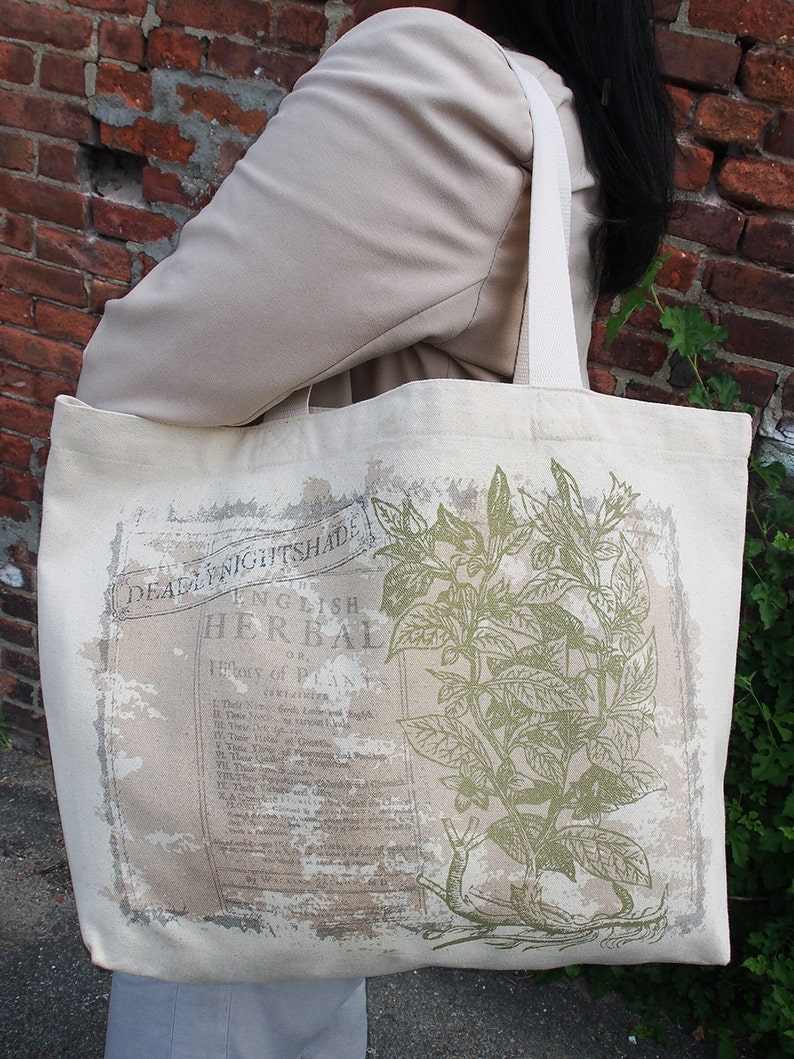 Op de afbeelding: Een witte canvas tote bag met een groene botanische illustratie en de tekst "English Herbal" en "Deadly Nightshade".