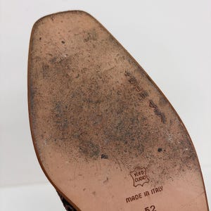 May include: Close-up of a worn brown leather sole. The text "VIA SPIGA" is visible, along with "VERO CUOIO" and "MADE IN ITALY". The sole has a pointed toe and is slightly curved.
