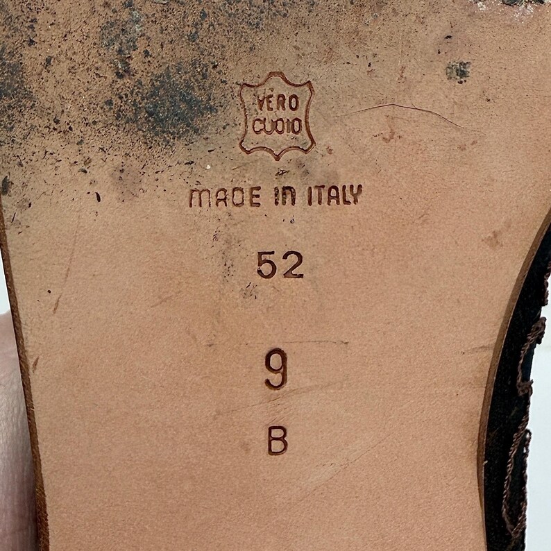 May include: Close-up of a shoe sole. The brown sole features the text "VERO CUOIO" in an emblem, and "MADE IN ITALY". The size is indicated as 9 B and 52.