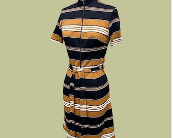 Puede incluir: Vestido de estilo vintage con rayas horizontales en negro, marrón claro y blanco. El vestido tiene cuello alto, mangas cortas y cremallera frontal. Incluye un cinturón a juego que ciñe la cintura. El vestido se exhibe en un maniquí.