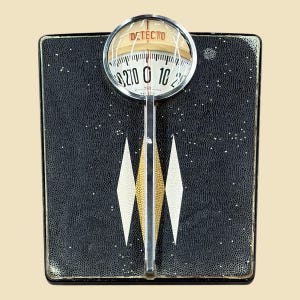 May include: Vintage DETECTO bathroom scale with a black textured surface and a chrome-plated magnifying dial. The dial displays weight in pounds, with a range up to 270 lbs. The scale features a decorative design with white and gold diamond shapes.