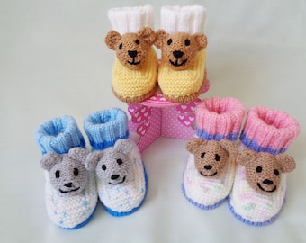 May include: Three pairs of knitted baby booties with bear faces. One pair is yellow, one pair is blue and white, and one pair is pink and white.