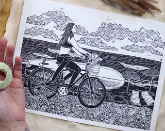 Lovely Day - hand-printed lino-cut block print - depicting a surfer biking to the beach - ocean, surf, swim, bicycle, outdoors, nature