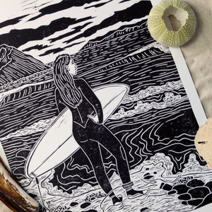 The Cove - hand-pressed lino-cut block print depicting a female shortboard surfer looking out at the ocean and waves - Nova Scotia Canada