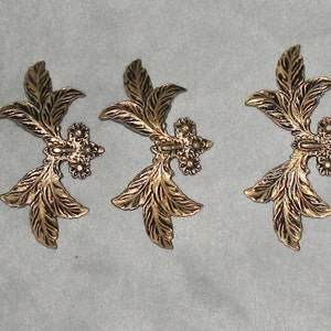 May include: Three gold-colored metal leaf-shaped embellishments with a textured surface.