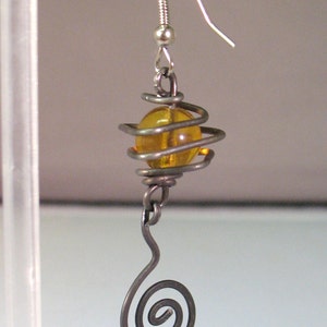 May include: A silver wire earring with a spiral design and an amber glass bead.