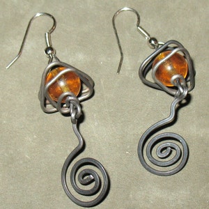 May include: A pair of silver earrings with amber glass beads and a spiral wire design.