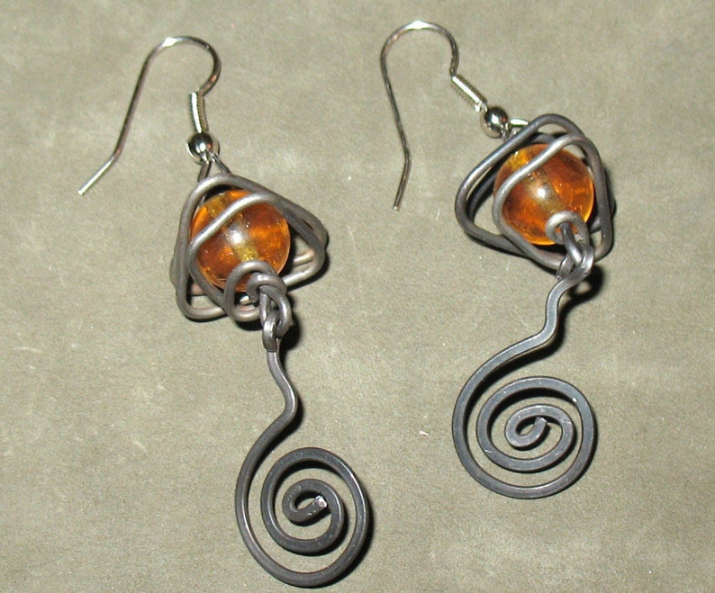 May include: A pair of silver earrings with amber glass beads and a spiral wire design.