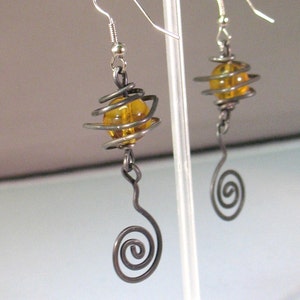 May include: A pair of silver earrings with amber glass beads wrapped in wire and a spiral design.