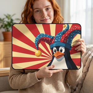 May include: A rectangular mousepad featuring a cartoon penguin wearing a jester's hat. The penguin is set against a red and yellow sunburst design. The hat is blue with white polka dots and gold bells.