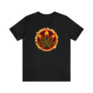 May include: Black t-shirt with a graphic of a green marijuana leaf surrounded by flames.
