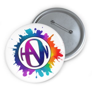 May include: A white button with a colorful watercolor splatter design. The center of the button features a white circle with the letters "AW" in a purple and blue font.