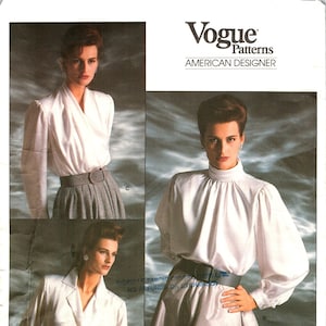 May include: A vintage sewing pattern for a white blouse with a high neck and long sleeves. The pattern is by Oscar de la Renta and is from Vogue Patterns, American Designer. The pattern number is 1913.