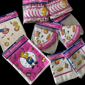 May include: Party supplies featuring The Simpsons characters. The image shows pink and white paper plates, napkins, and tablecloths. The packaging includes the text "THE SIMPSONS" and "Partytime".