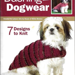 May include: A book cover titled Dashing Dogwear featuring the text 7 Designs to Knit and Created for Leisure Arts by House of White Birches. The cover displays a white and brown Shih Tzu dog wearing a maroon knitted sweater with textured stripes.